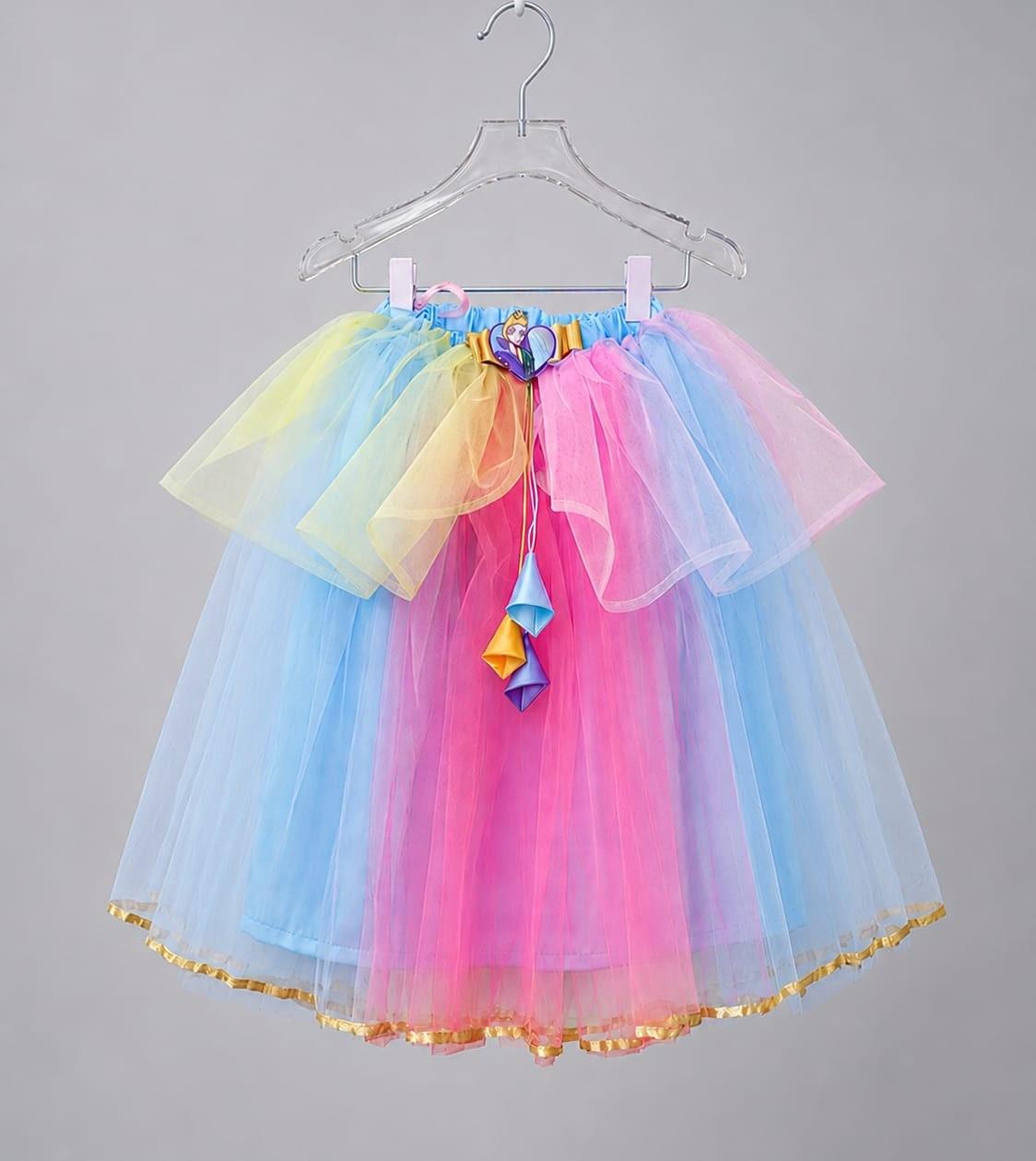 Pastel katmanlı tül etek, askıda, sade fon önünde: mavi, pembe ve sarı tül, altın şeritli etek ucu.